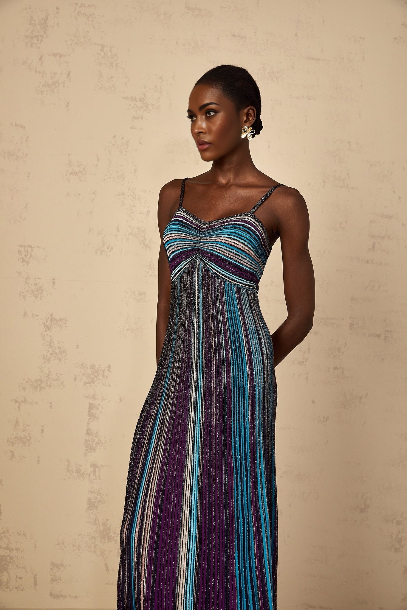 A purple maxi dress with sequin stripes on a knit fabric worn by a woman standing in a relaxed pose