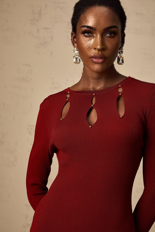 A red knit midi dress with long sleeves beaded details and cutout accents worn by a model against a plain background
