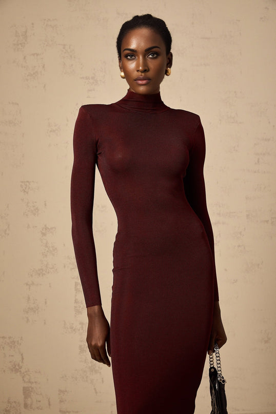 A red knitted midi dress with a semi sheer design worn by a model standing against a plain background