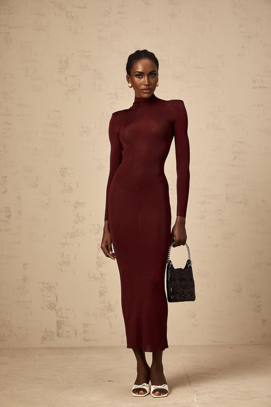 A red knitted midi dress with a semi sheer design worn by a model standing against a plain background