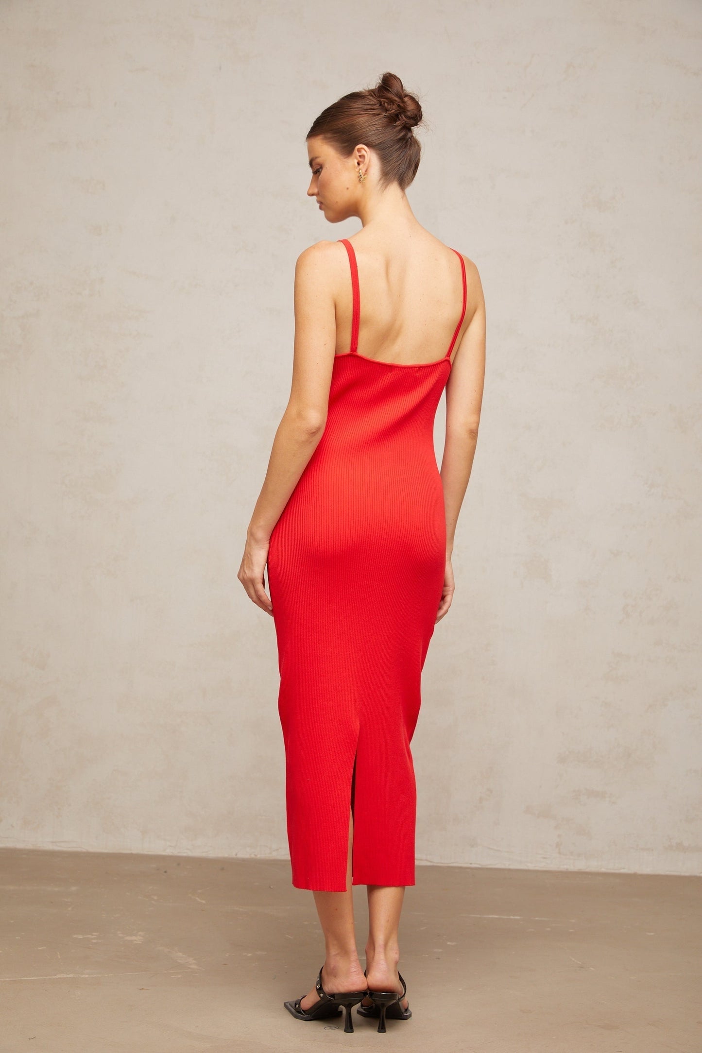 A red knitted midi dress with pin details featuring a formfitting silhouette and long sleeves