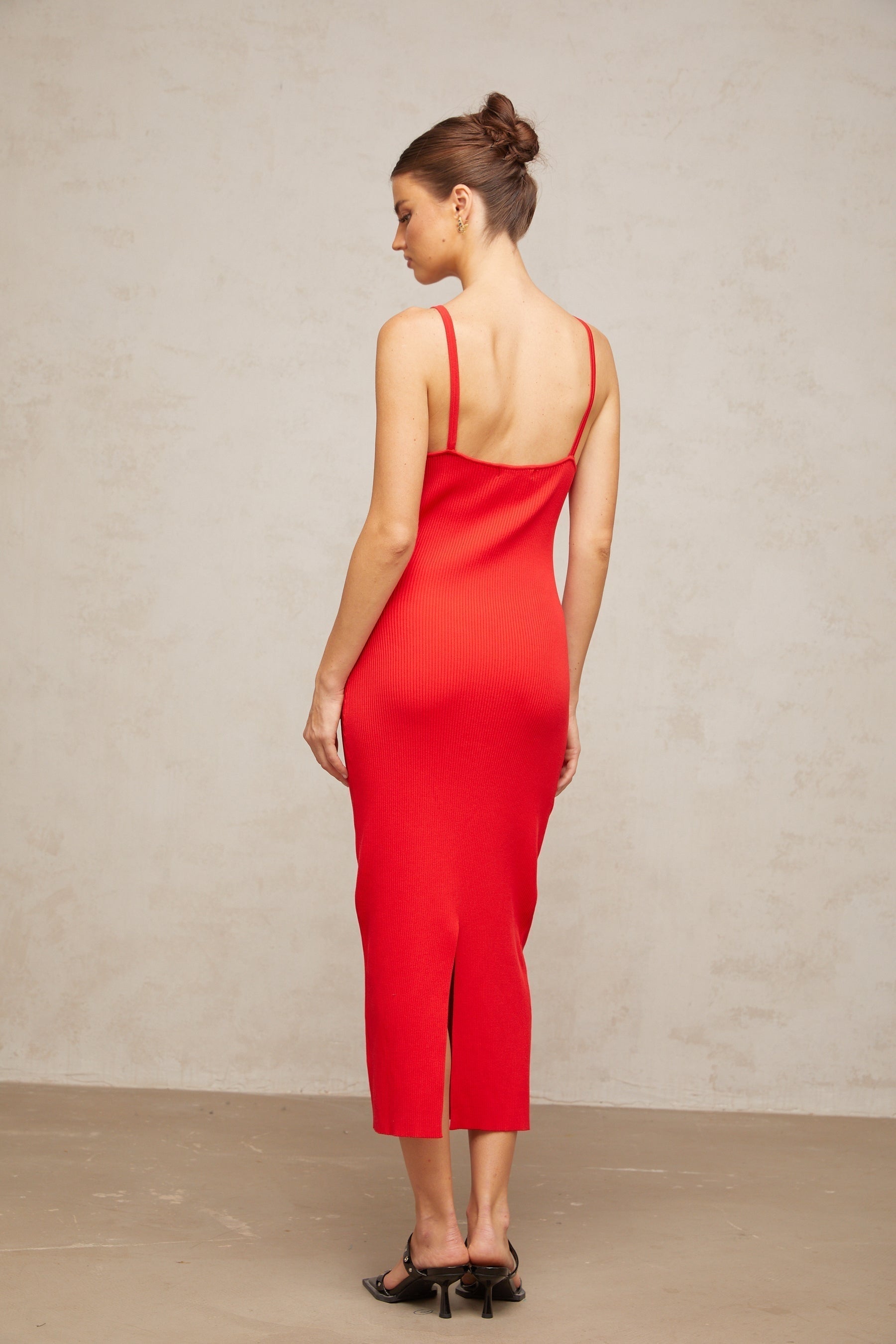 A red knitted midi dress with pin details featuring a formfitting silhouette and long sleeves