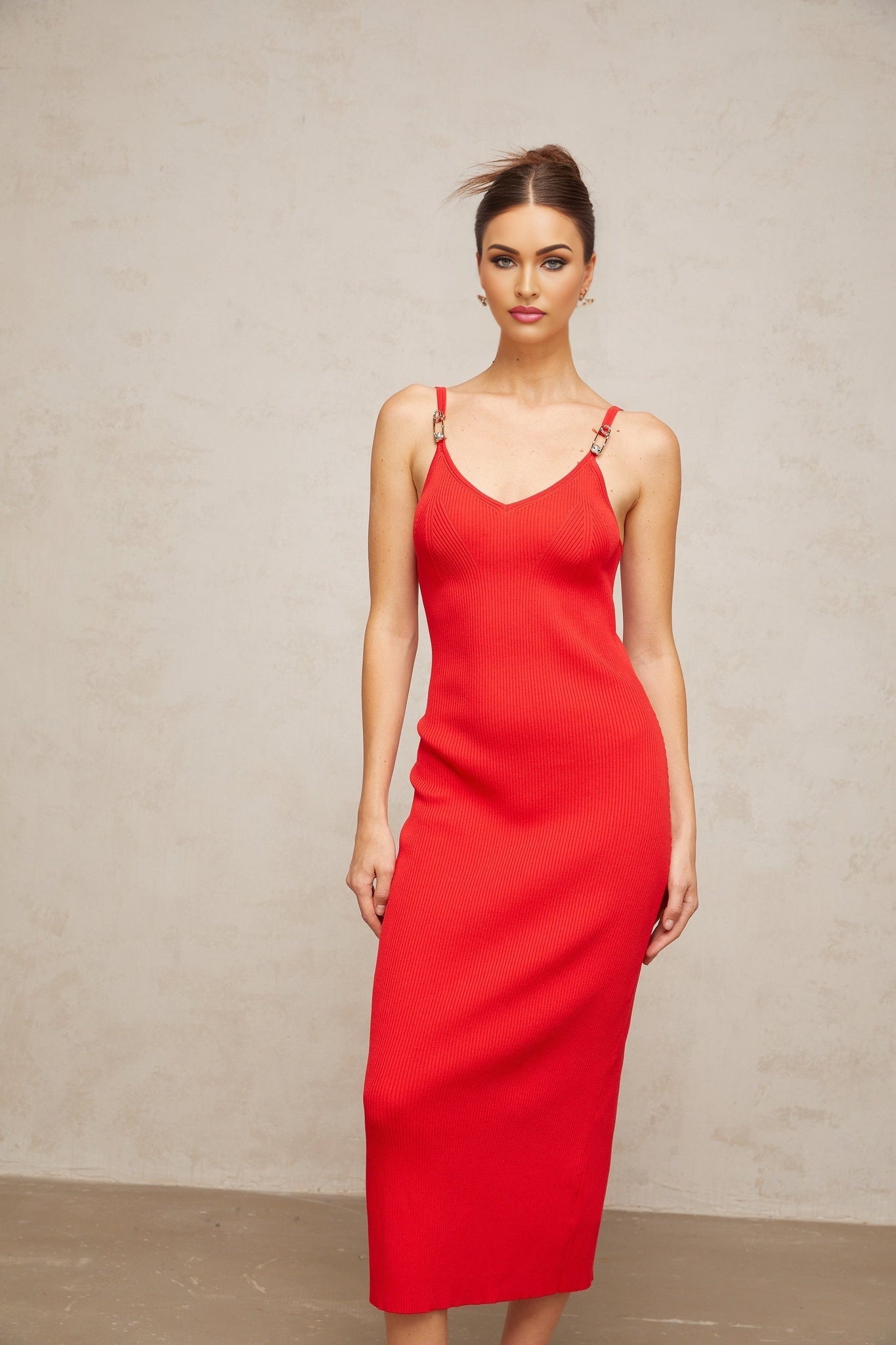 A red knitted midi dress with pin details featuring long sleeves and a fitted silhouette