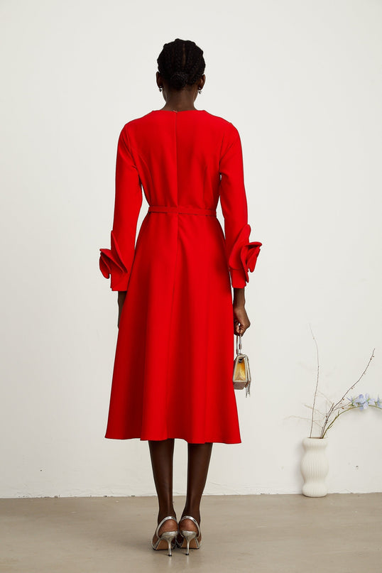 A red long sleeve dress with a floral pattern worn by a model standing against a plain background