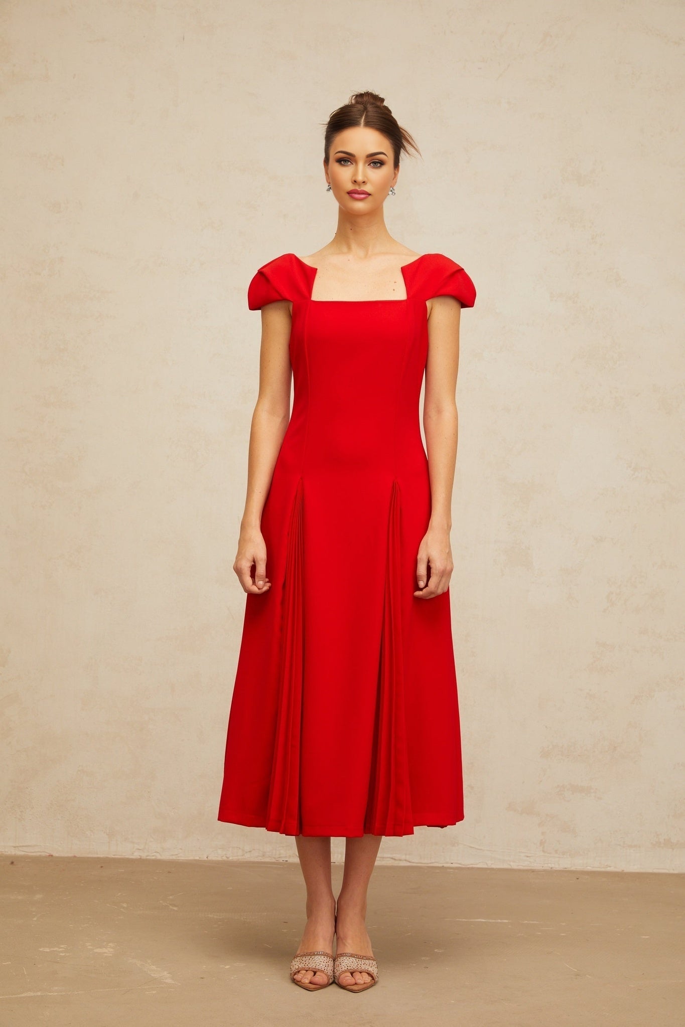 A red midi dress with pleated details and a flared skirt featuring a Gervaise design