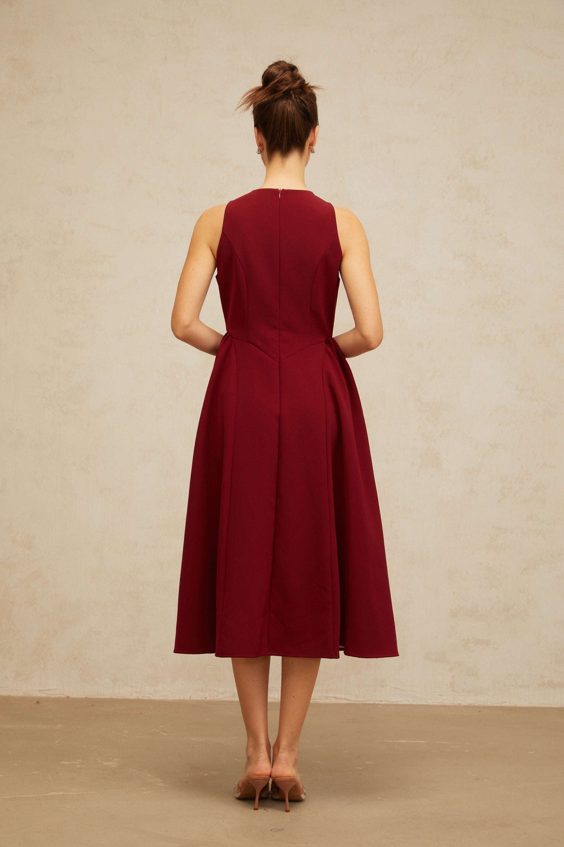 A red midi tank dress with a floral pattern featuring pleats and a fitted waist The dress has a vibrant flower motif throughout and falls to mid calf length
