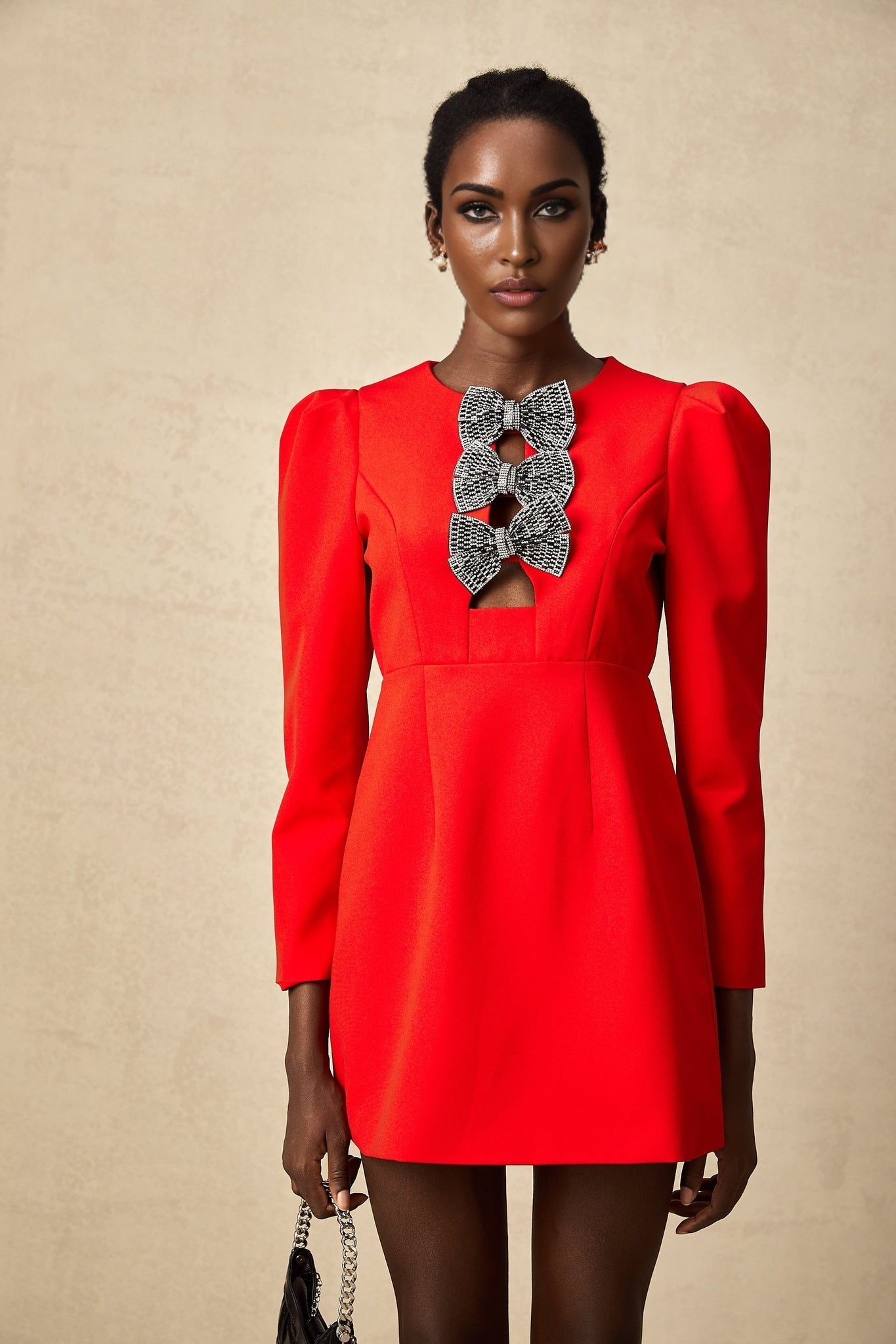 A red mini dress with a split skirt featuring a studded bow accent and a short hemline