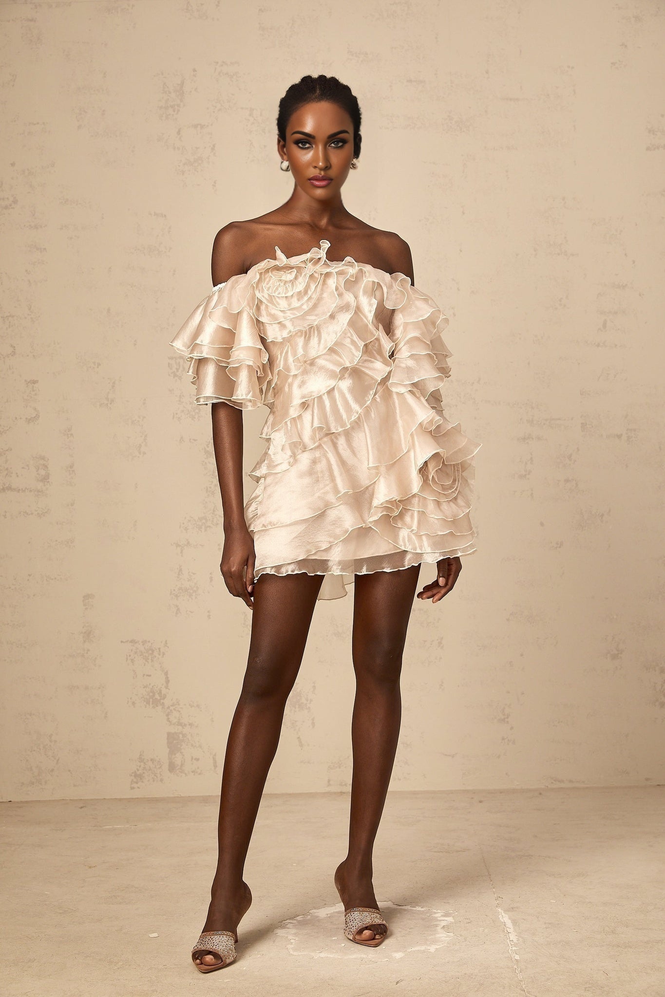 A short asymmetric mini dress in neutral tones featuring a cerise pink flounce detail and one shoulder design