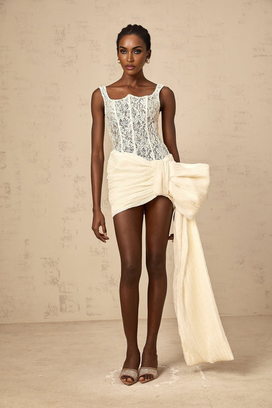 A short beige mini dress with floral lace pattern featuring a bow detail and a pencil skirt silhouette