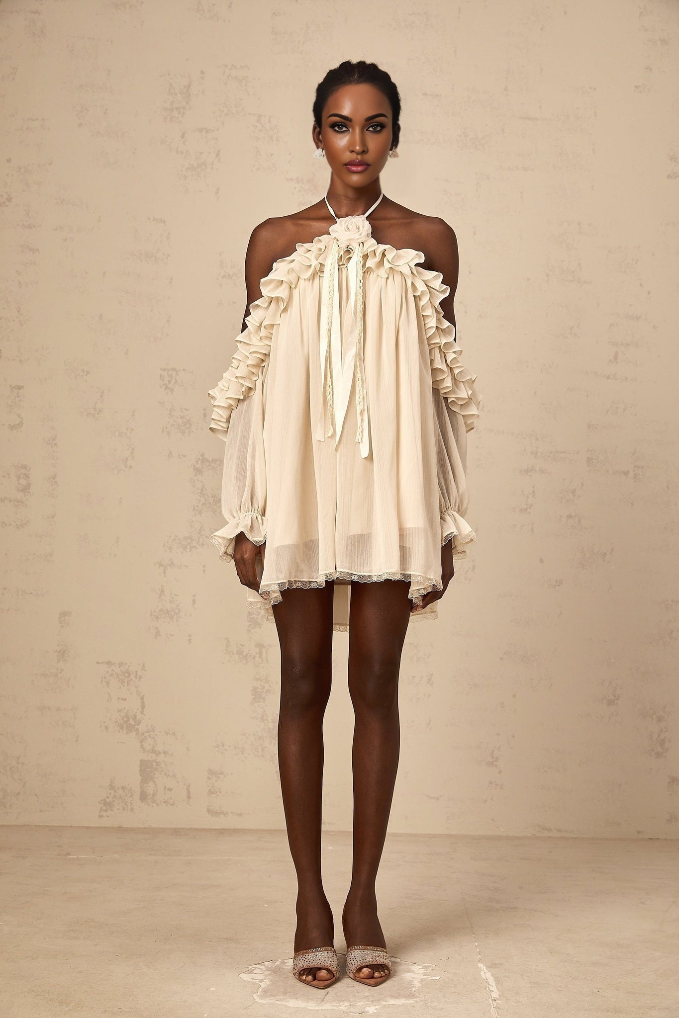 A short beige mini dress with ruffled details and delicate floral appliques scattered across the fabric