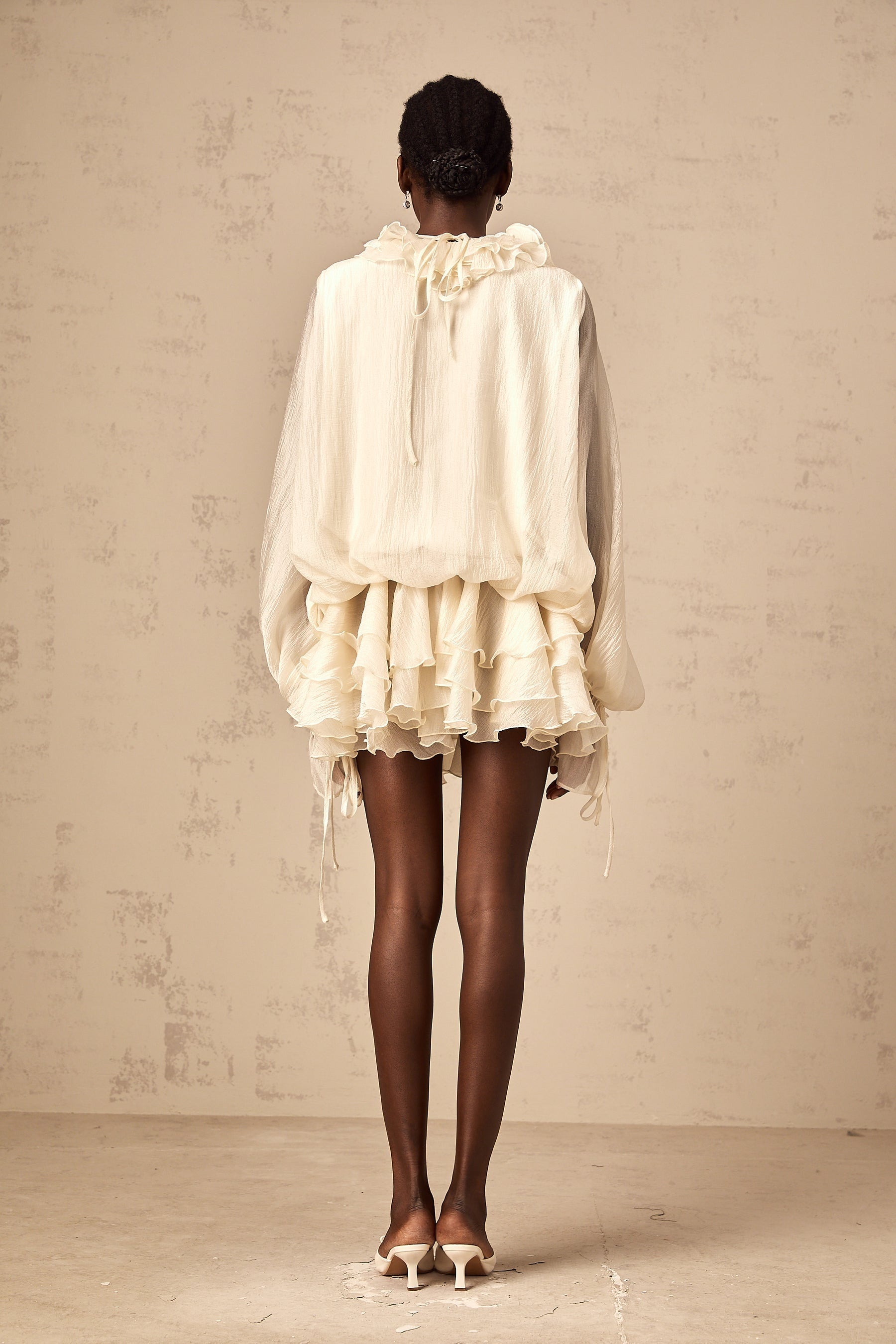 A short beige tiered mini dress with floral applique details and a feminine silhouette named Zephyrine