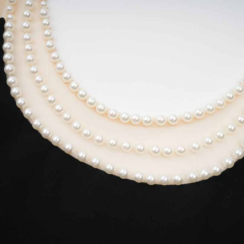 A short black mini dress adorned with faux pearl embellishments called Danae