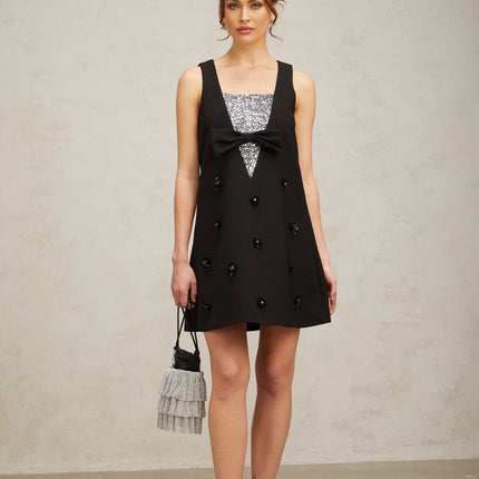 A short black mini dress with 3D petal shaped sequins covering the fabric creating a textured floral pattern