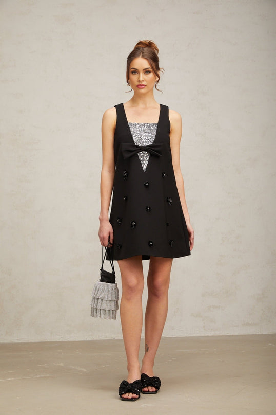 A short black mini dress with 3D petal shaped sequins covering the fabric creating a textured floral pattern