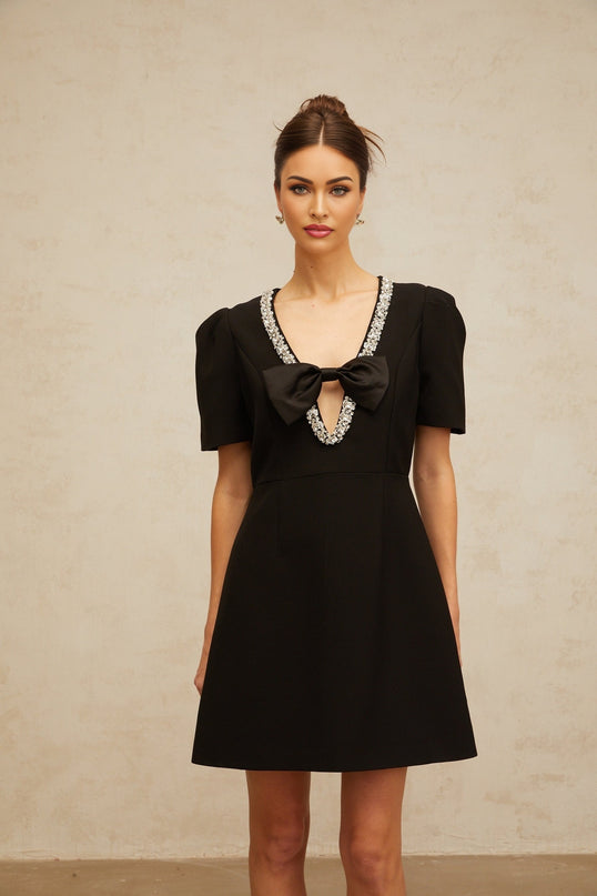 A short black mini dress with a prominent bow embellishment