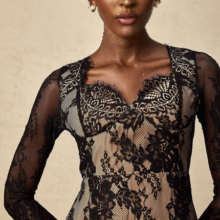 A short black mini dress with delicate floral embroidery on lace fabric featuring a fitted silhouette and intricate lace detailing