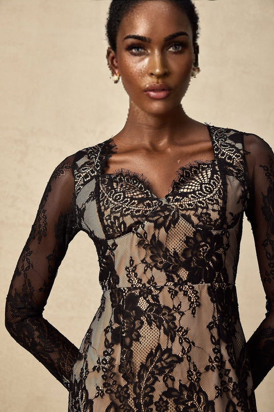 A short black mini dress with delicate floral embroidery on lace fabric featuring a fitted silhouette and intricate lace detailing