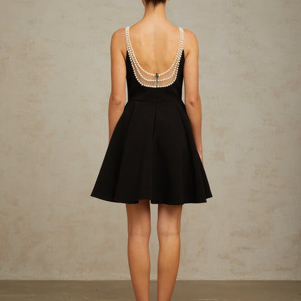 A short black mini dress with faux pearl embellishments named Danae