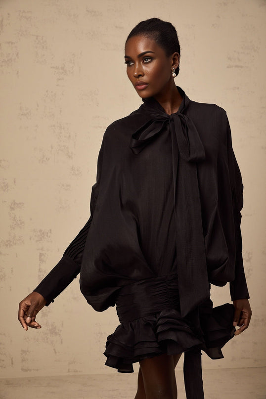 A short black mini dress with ruffled details and a pussybow neckline called the Melanie dress