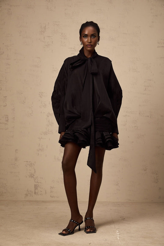 A short black mini dress with ruffled details and a pussybow neckline named Melanie