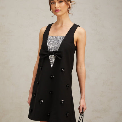 A short black mini dress with threedimensional petal shaped sequins covering the fabric creating a textured and shimmering effect