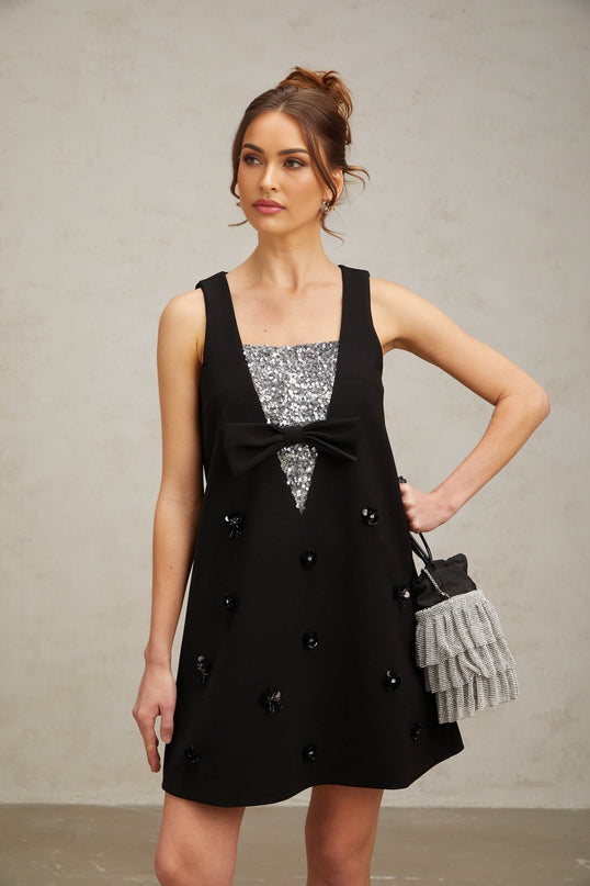 A short black mini dress with threedimensional petallike sequins covering the fabric creating a textured and sparkly effect