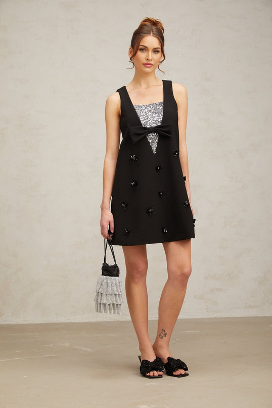 A short black mini dress with threedimensional petalshaped sequins covering the fabric creating a shimmering textured effect