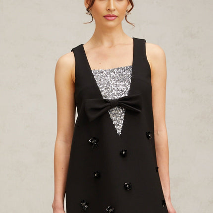A short black mini dress with threedimensional petalshaped sequins covering the fabric creating a textured and shimmering effect