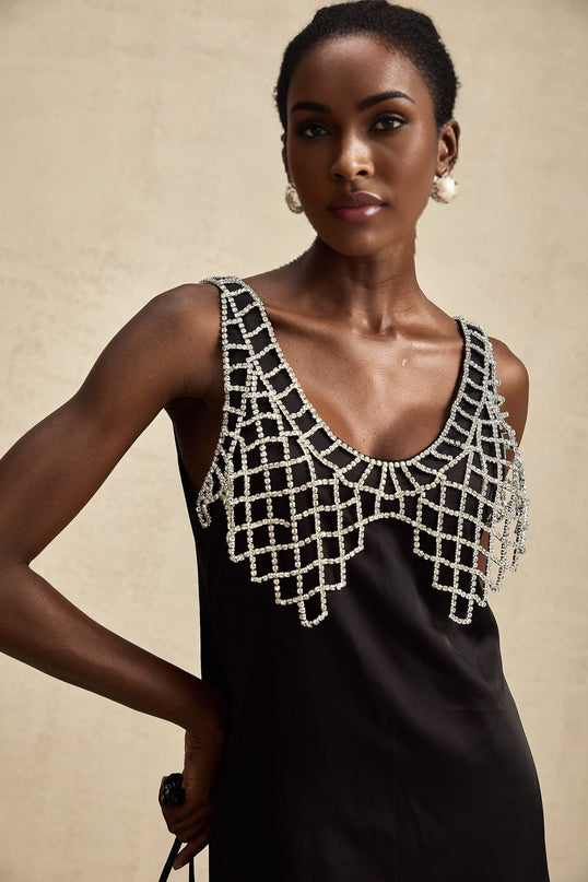 A short black satin mini dress adorned with sparkling crystal embellishments featuring a sleek silhouette and delicate straps