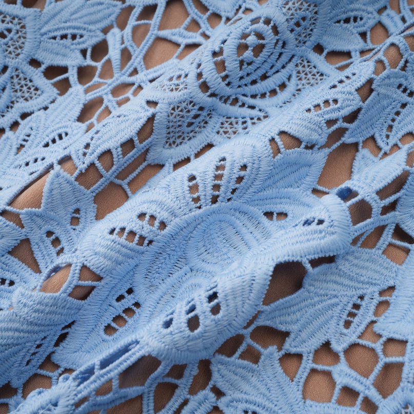 A short blue dress with floral lace appliques and ruffled details