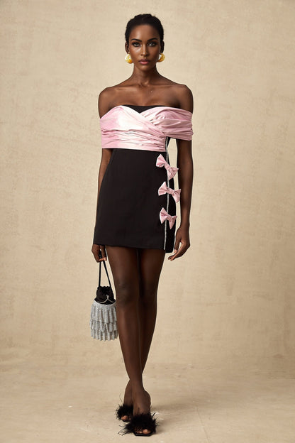 A short colorblocked mini dress with a bow embellishment in contrasting colors featuring a fitted silhouette and feminine design details