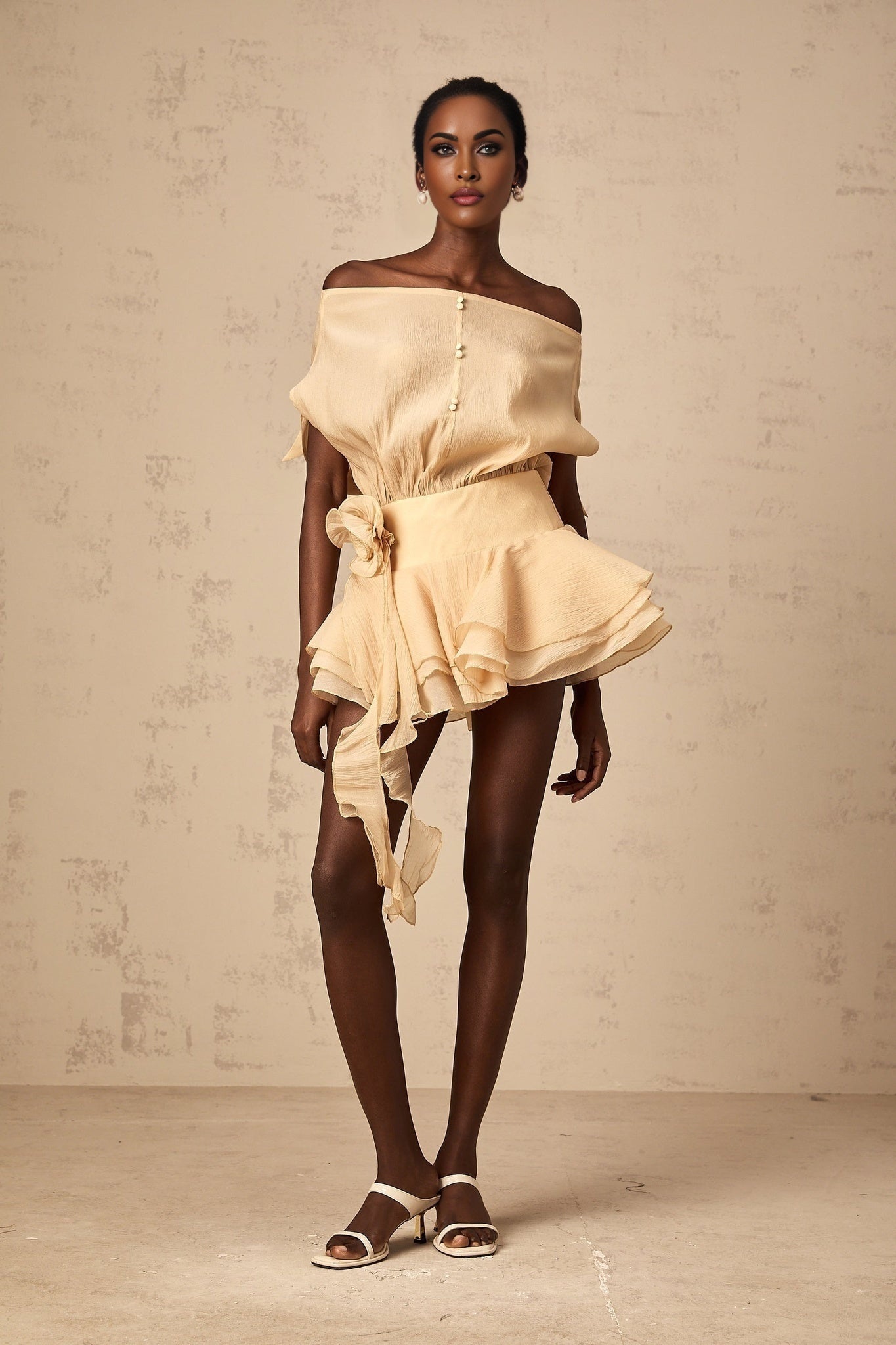A short floral dress with ruffle details and floral applique decorations on a light colored fabric