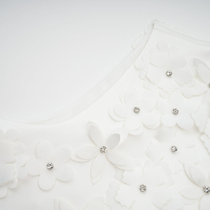 A short floral print dress with a fitted bodice and flared skirt featuring a colorful faux flower pattern on a light background