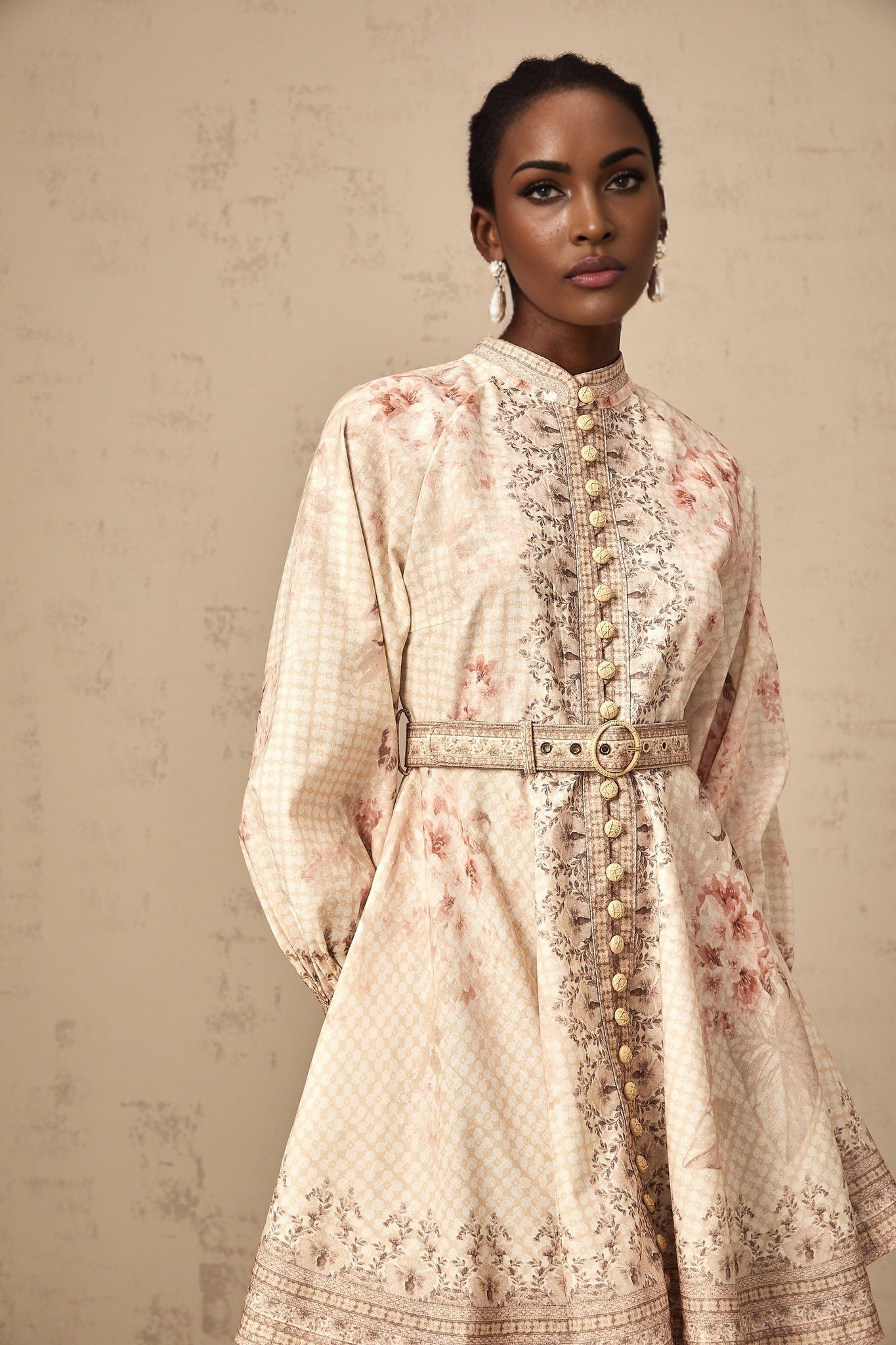 A short floral print mini dress with a belt accent cinched at the waist featuring a vibrant pattern and feminine silhouette