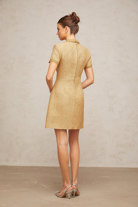 A short gold mini dress with sequin embellishments and a tweed texture shimmering in the light