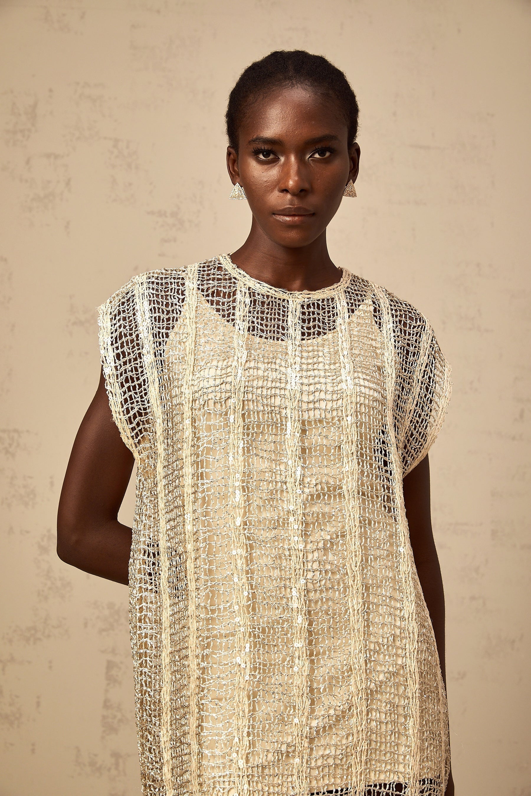 A short gold mini dress with sequin embellishments and cut out details on a model