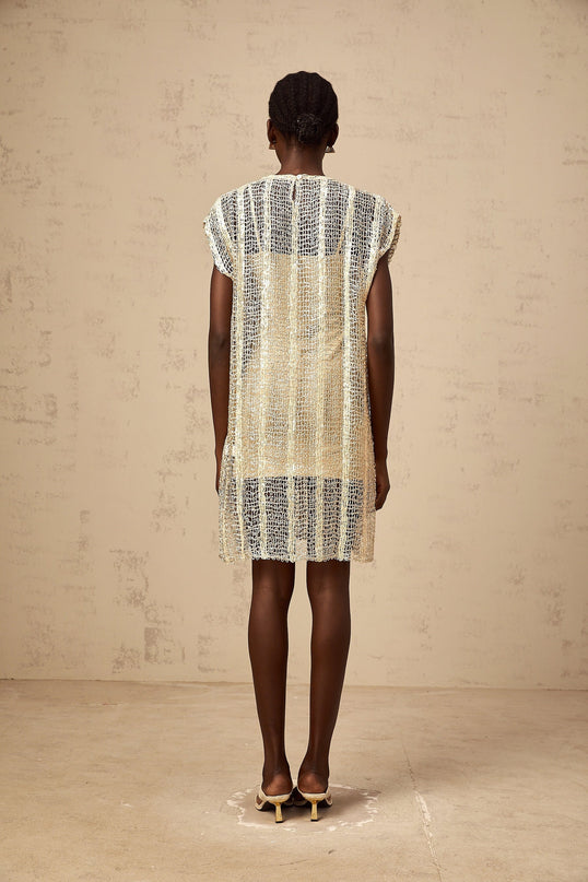 A short gold mini dress with sequin embellishments and cutout details on a fashion model