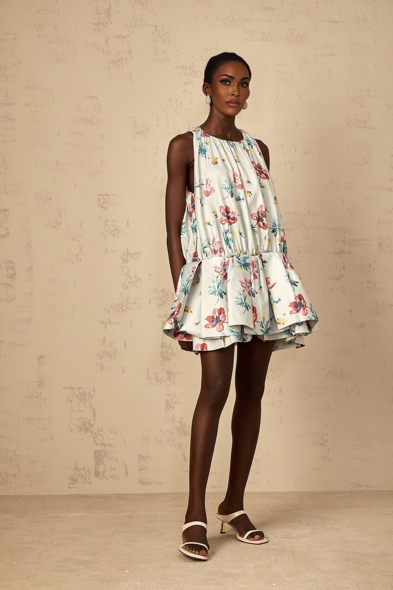 A short green dress with a floral print pattern and shirred details featuring a mini length design