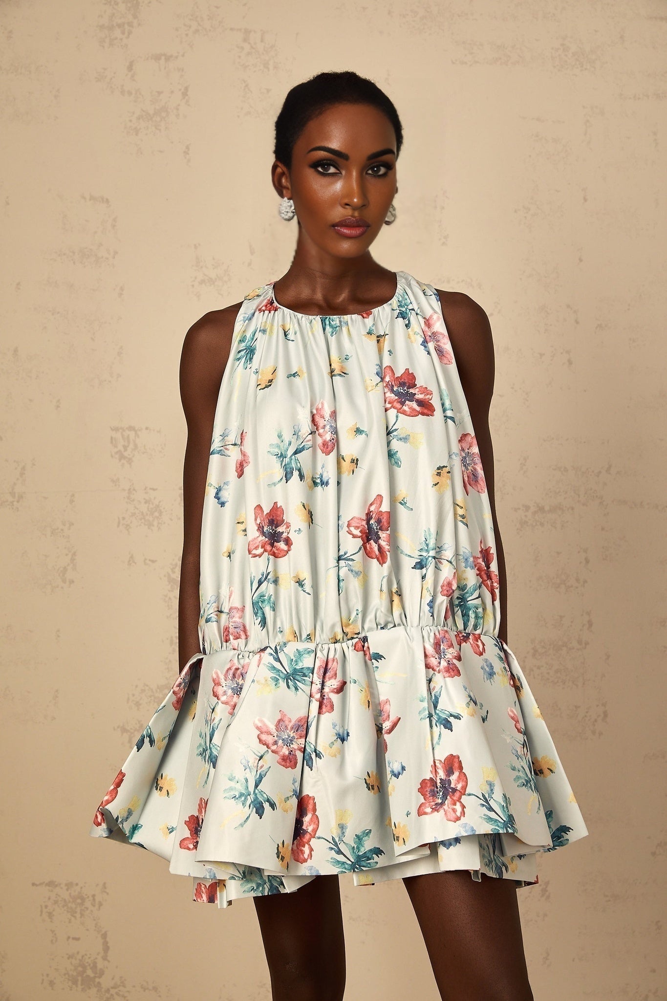 A short green dress with a floral print pattern and shirred fabric details featuring a mini length design