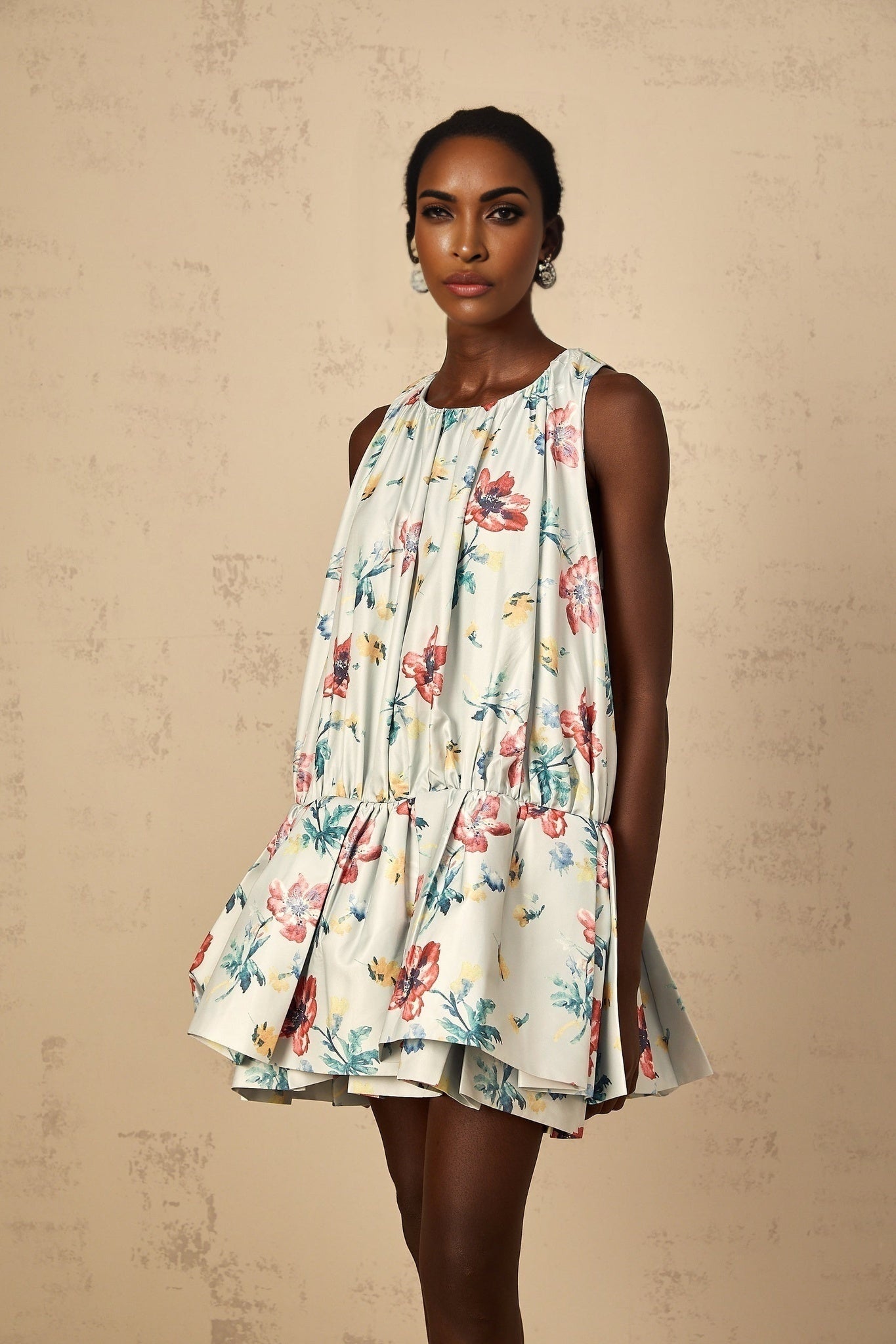 A short green dress with floral print and shirred details featuring a mini length and a feminine silhouette