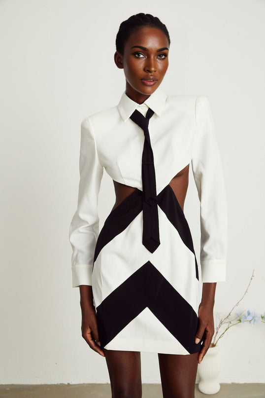 A short light colored mini dress with a high neckline and neck tie detail featuring cutout sections on the sides and back