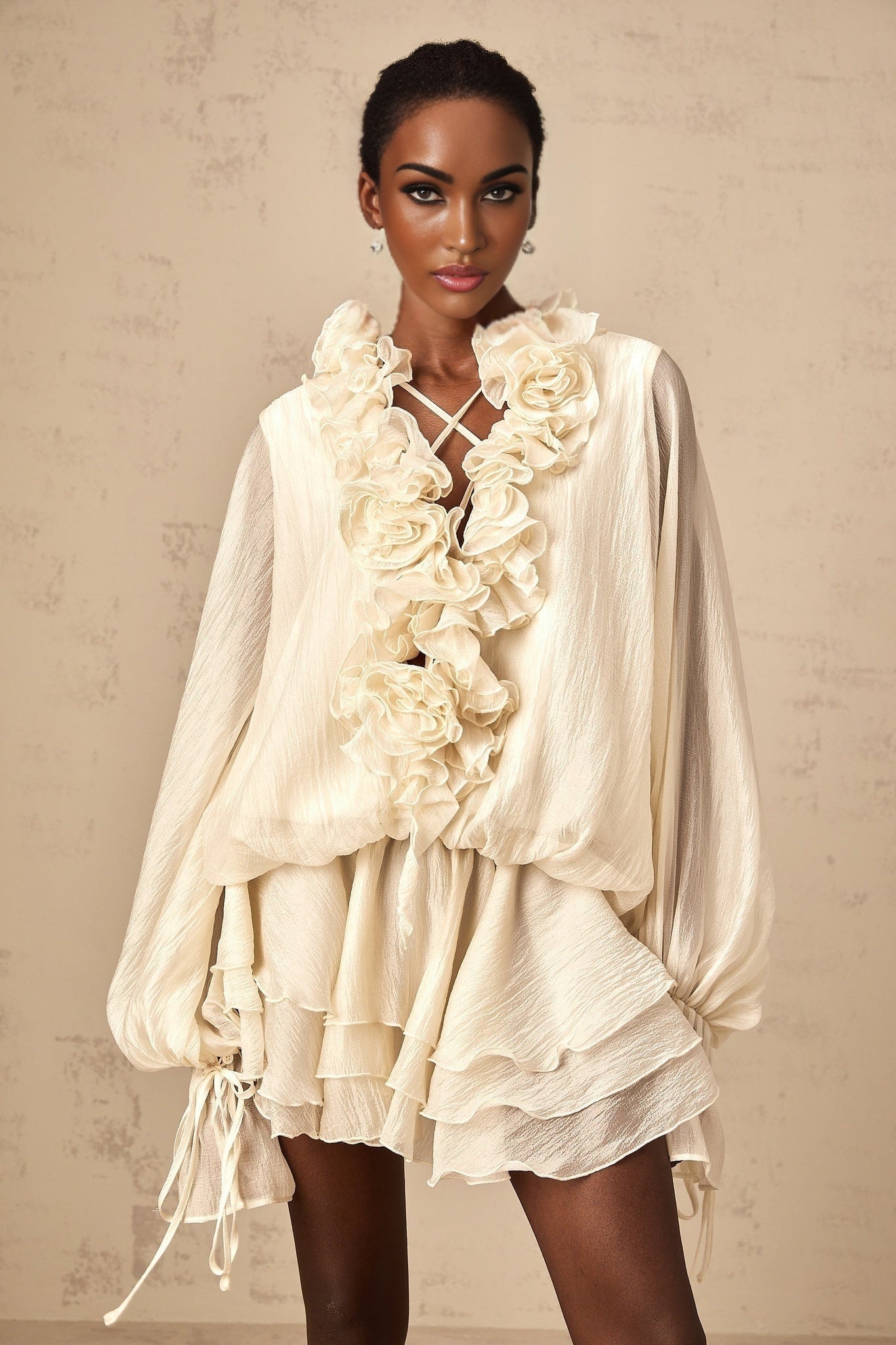 A short light colored tiered mini dress with floral applique details called Zephyrine