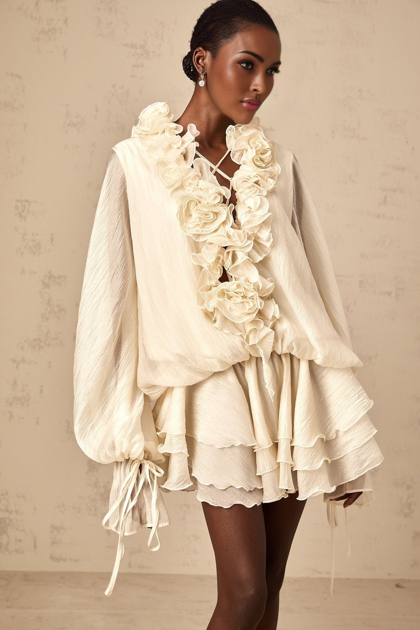 A short neutral colored tiered mini dress with floral applique details named Zephyrine
