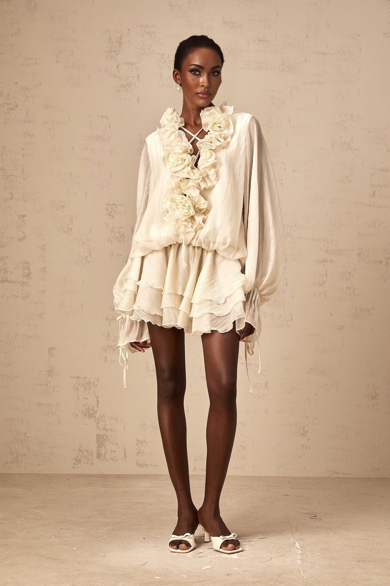 A short neutral colored tiered mini dress with floral applique details on the bodice and skirt named Zephyrine