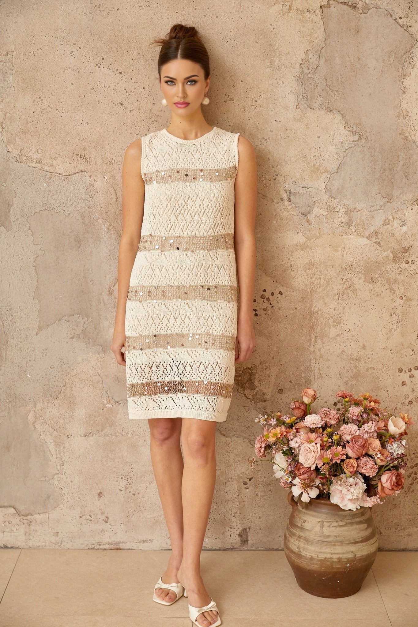 A short offwhite mini dress with sequin embellishments and a crochetknit texture featuring a delicate feminine design