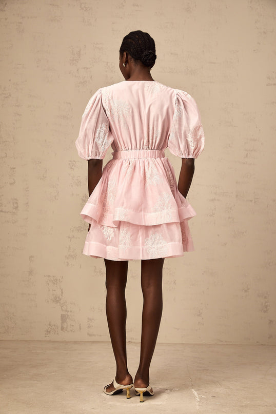 A short pink dress with floral embroidery and layered skirt detail