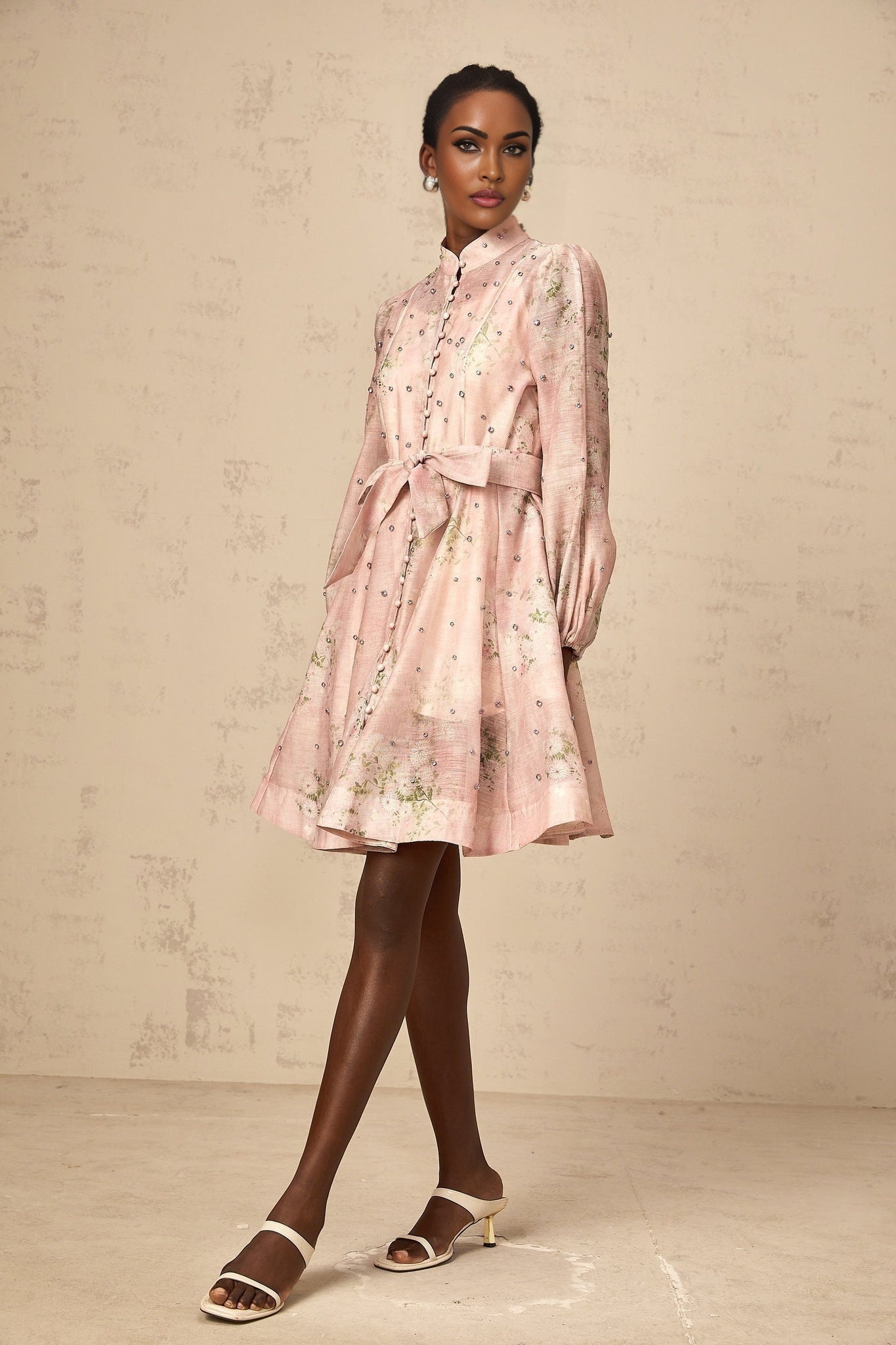 A short pink dress with floral print pattern and embellishments featuring a fitted silhouette and mini length