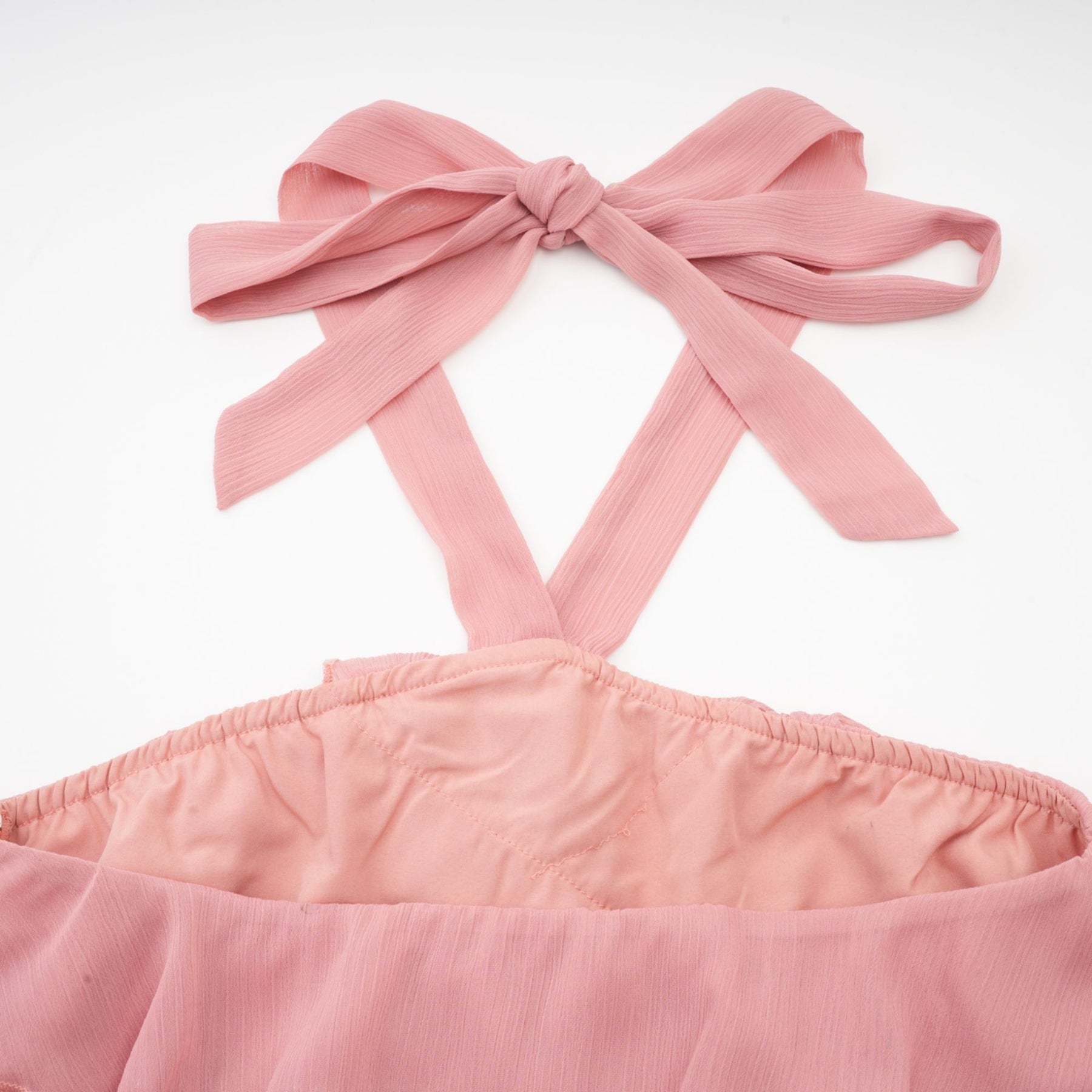A short pink mini dress with a halter neckline and tiered skirt design in a briar rose shade