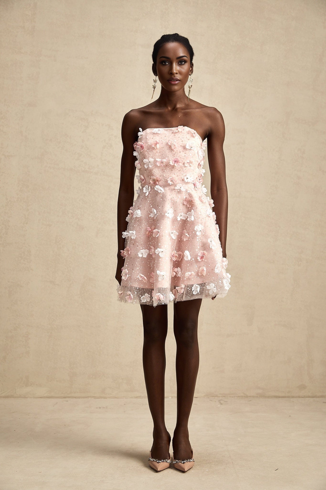 A short pink mini dress with a puffy silhouette featuring three dimensional petal details covering the entire garment creating a floral textured appearance