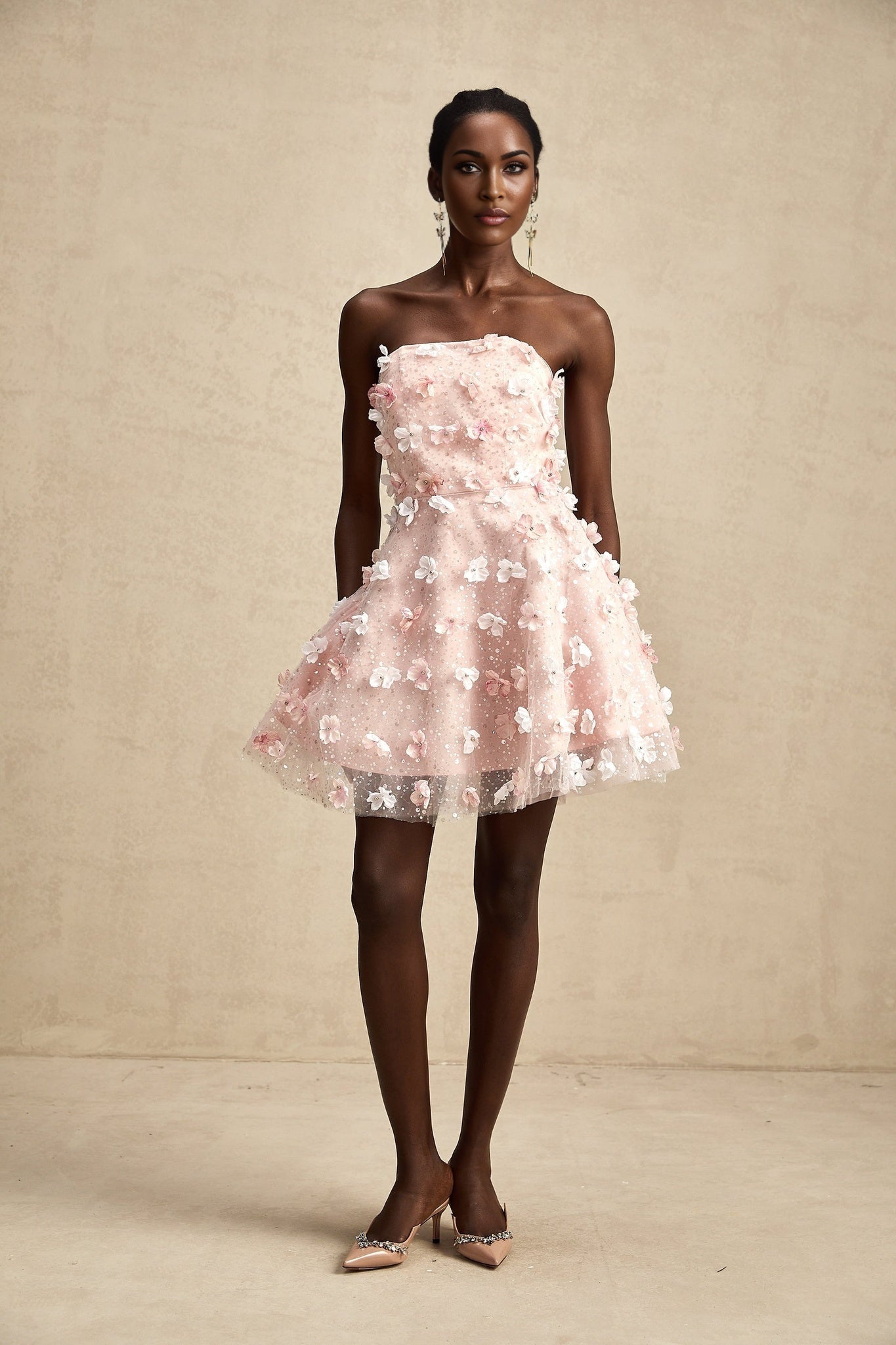 A short pink mini dress with puffy sleeves and a skirt adorned with threedimensional flower petal details creating a textured floral effect